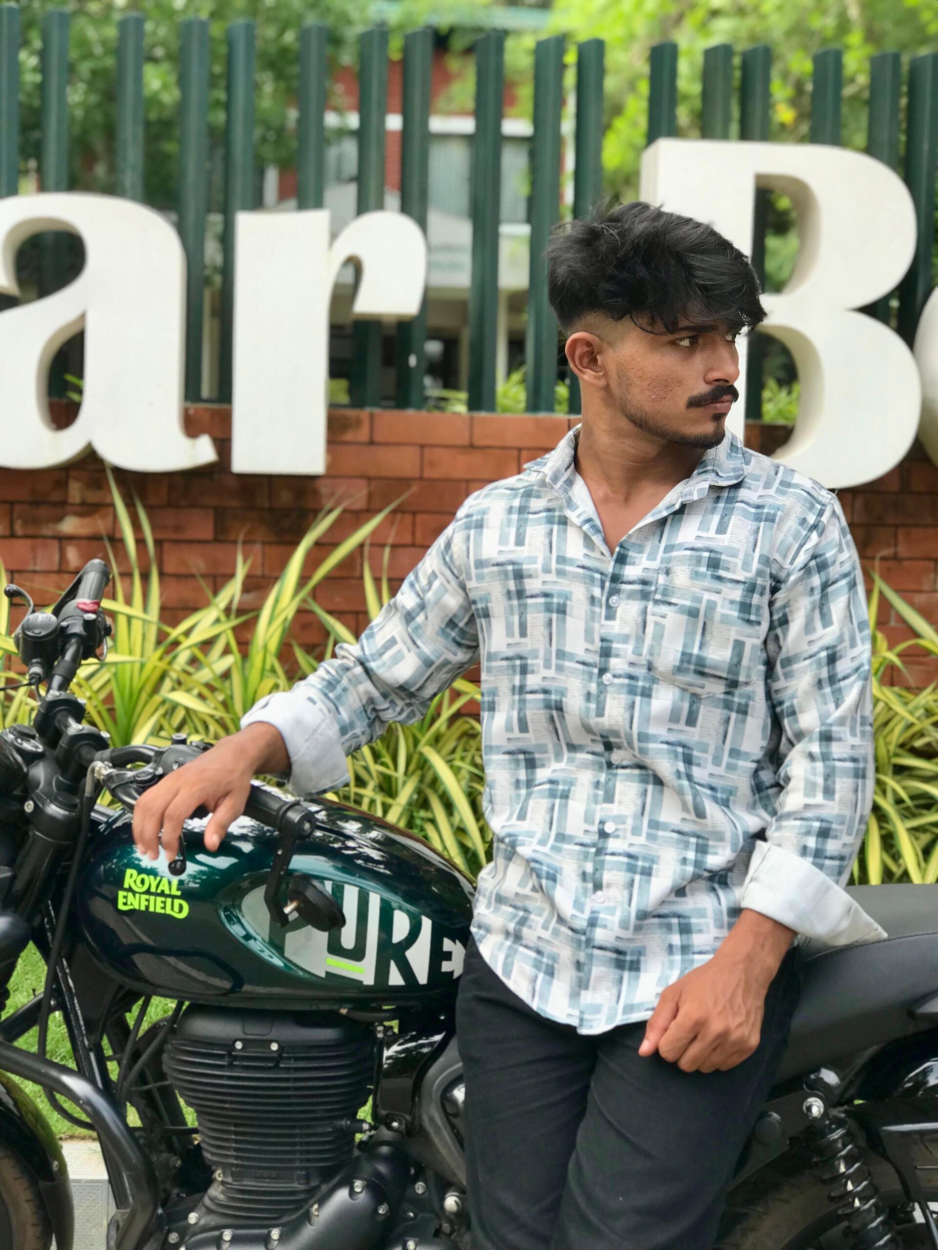 “Aromal - Digital marketing specialist in Calicut standing beside a Royal Enfield motorcycle, looking confident in an outdoor setting.”